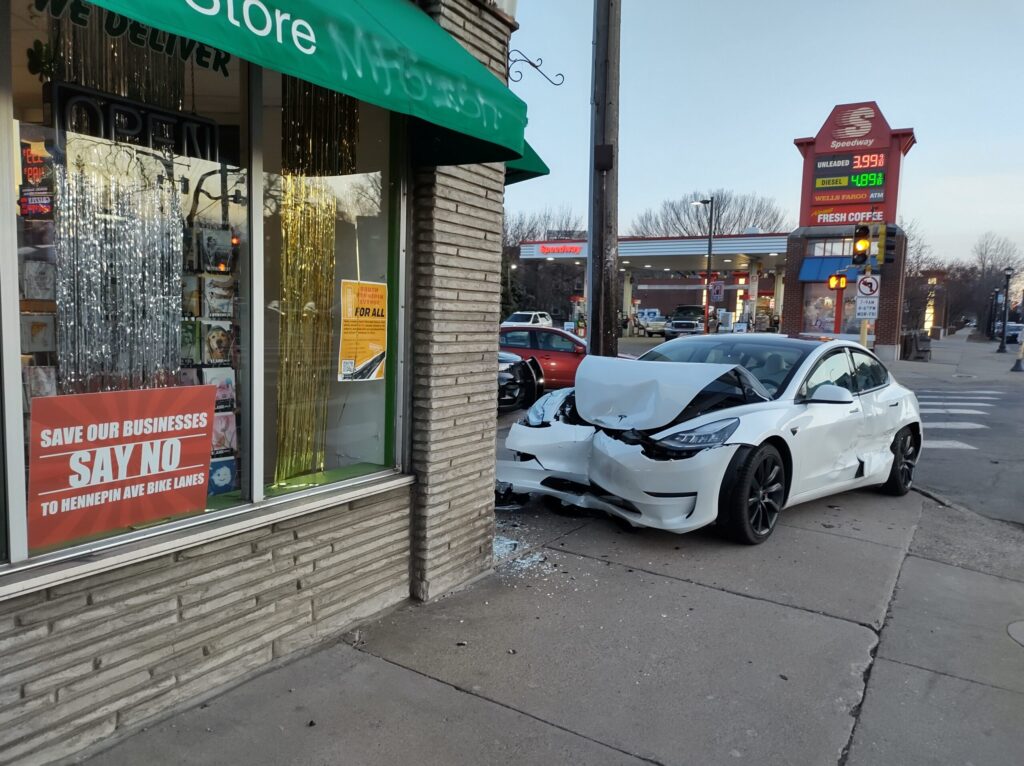 Tesla crashed into Hennepin Avenue business. Business has sign that says: Save Our Businesses Say No To Hennepin Ave Bike Lanes.