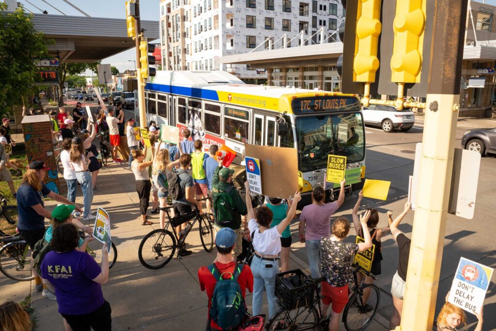 Post march people gathered at Uptown Transit Station holding signs in support of full-time bus lanes